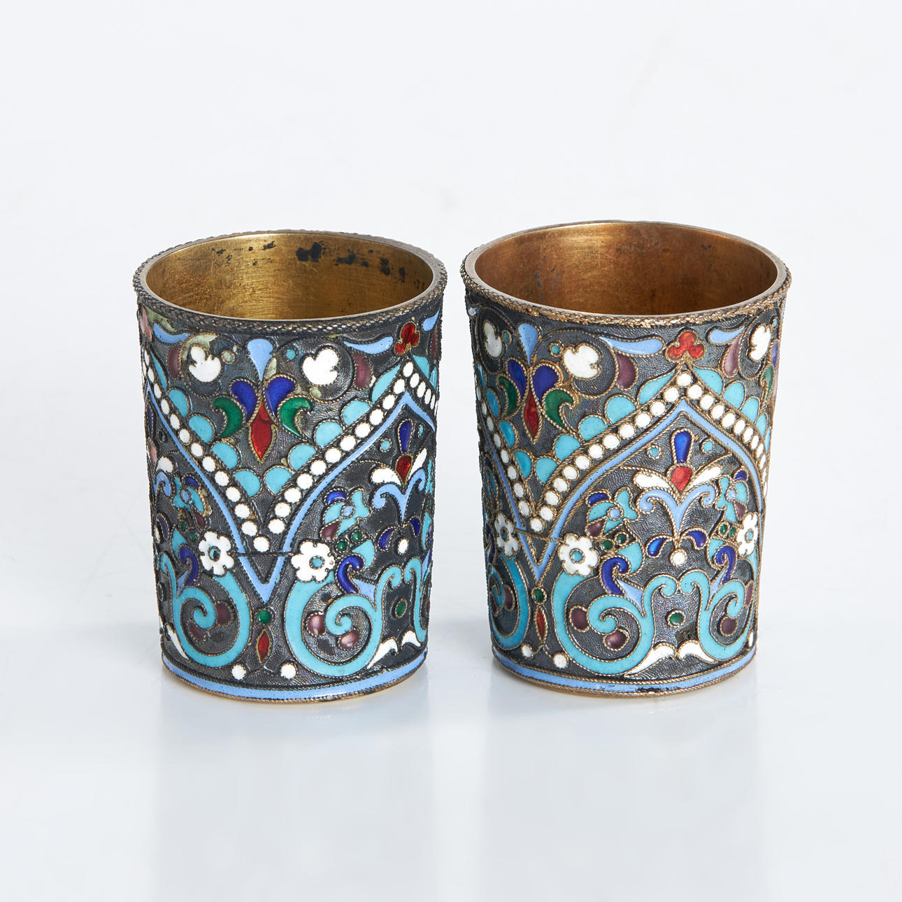 VODKA CUPS, a pair, silver, by Dmitriì Nikolaevich Nikolaev, Comptroller Ivan Sergeyevich Lebedkin, Moscow, Russia 1898-1908, gilt, richly enamelled.