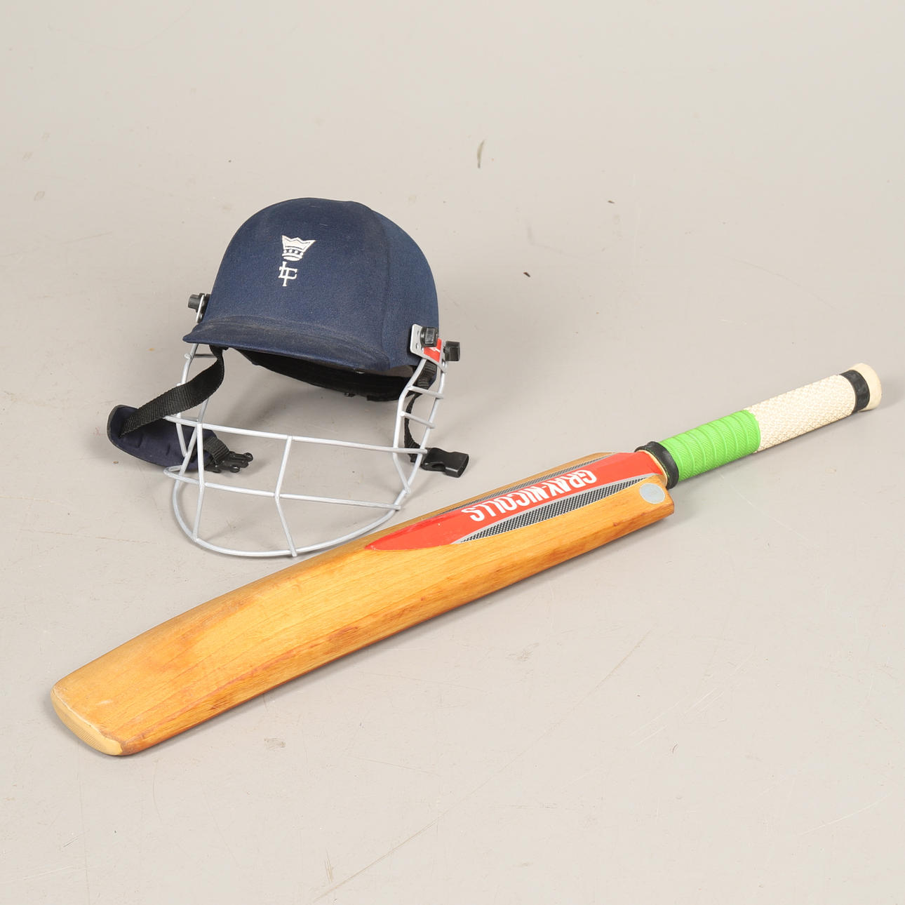 EN GRÅ NICHOLS CRICKET BAT OCH HJÄLM.