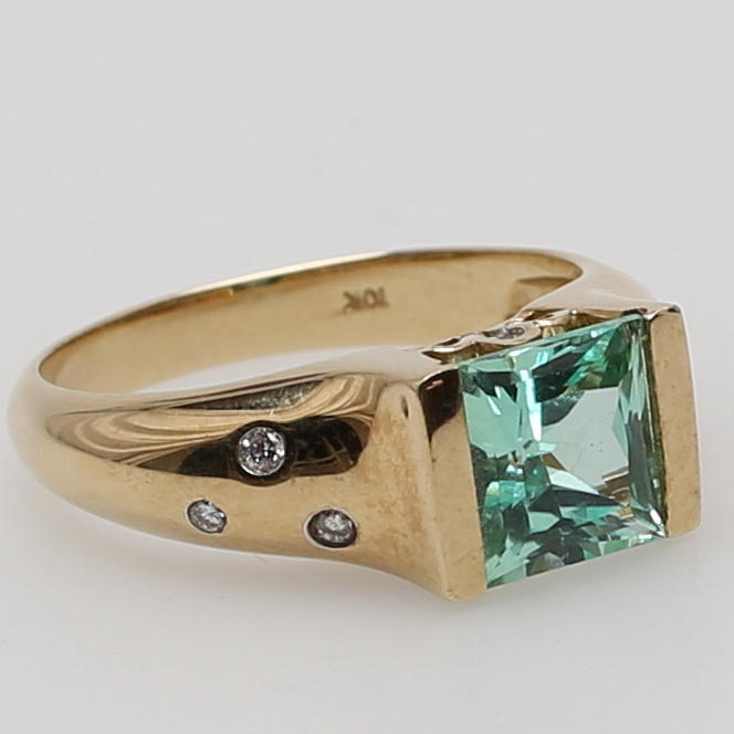 RING i 10K gulguld besatt med ljusgrön syntetisk safir samt åtta diamanter.