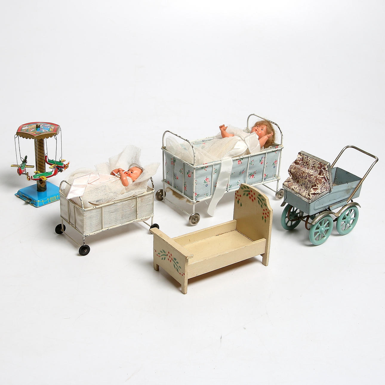 LEKSAKER, 7 delar, bl.a. dockor, järnsängar samt dockvagn i plåt. 1900-talets första hälft.