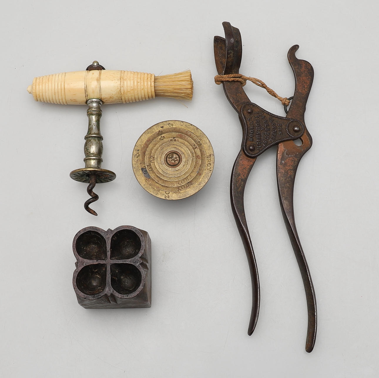A BONE HANDLED CORKSCREW, A SET OF NESTING WEIGHTS, A PRINTING BLOCK, AND A CAST IRON CORKSCREW.