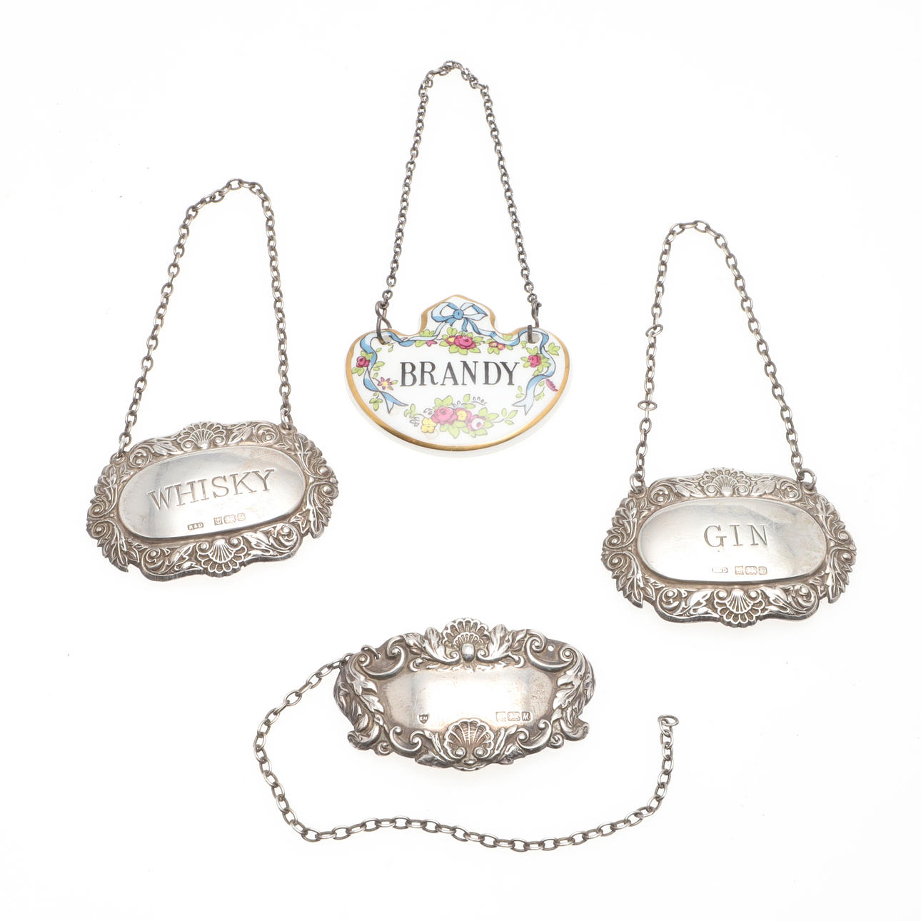 A CERAMIC AND THREE OTHER SILVER DECANTER LABELS.