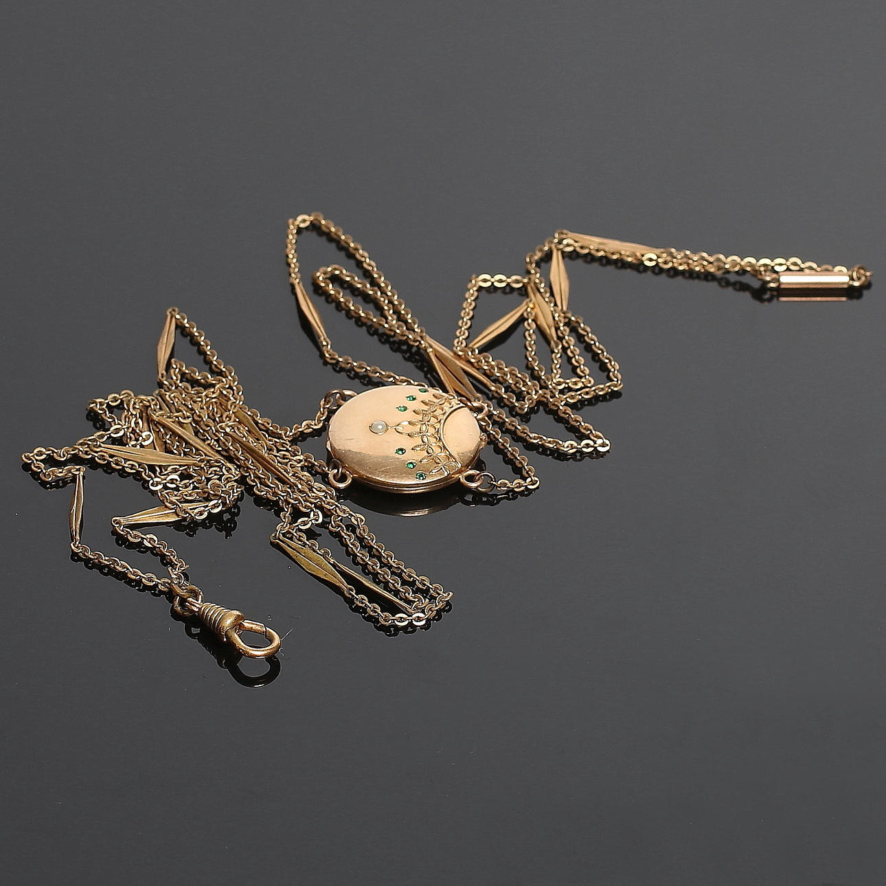 HALSBAND samt KLOCKKEDJA med MEDALJONG, förgylld gulmetall samt gröna stenar och orientalisk pärla. Sekelskiftet 1800/1900-.