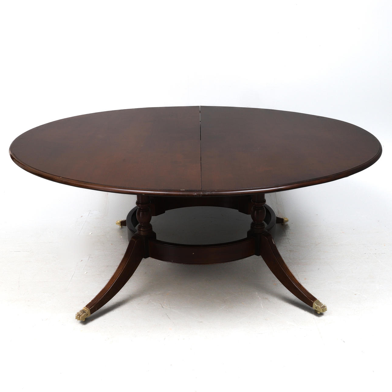A REPRODUCTION REGENCY STYLE MAHOGANY EXTENDING DINING TABLE.