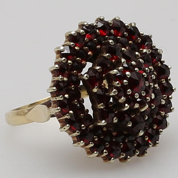 RING i 14K gulguld, rikligt besatt med fasettslipade granater.