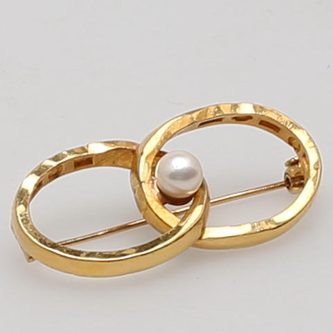 BROSCH i 23K gulguld, två bearbetade vigselringar besatt med pärla.