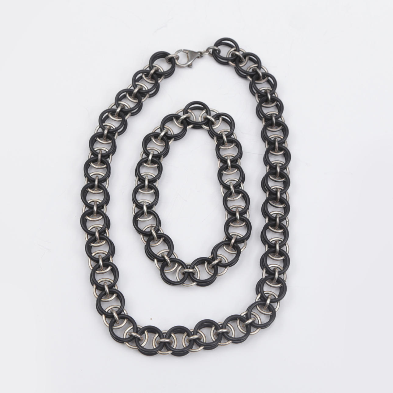 HALSKÆDE og ARMBÅND, sølv/gummi.