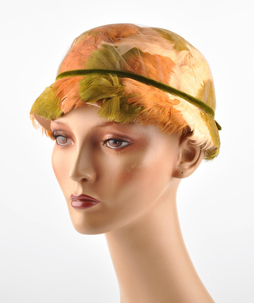 KOPFBEDECKUNG 3. damhatt befjädrade hatt. form av cloche, cloche hatt.