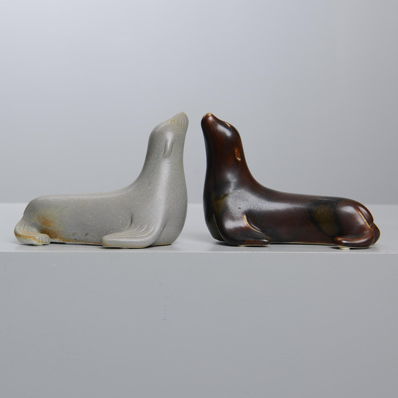 GUNNAR NYLUND. Two stone sea lions, Rörstrand, monogram signed.