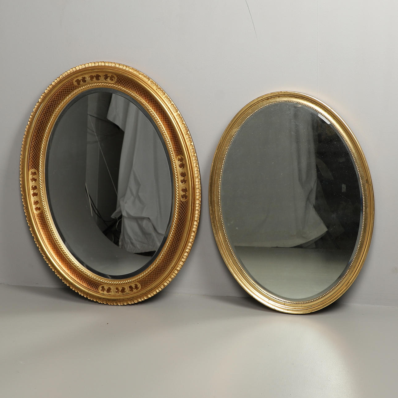 TVÅ MODERNA OVALA FÖRGYLLDA VÄGGSPEGLAR.