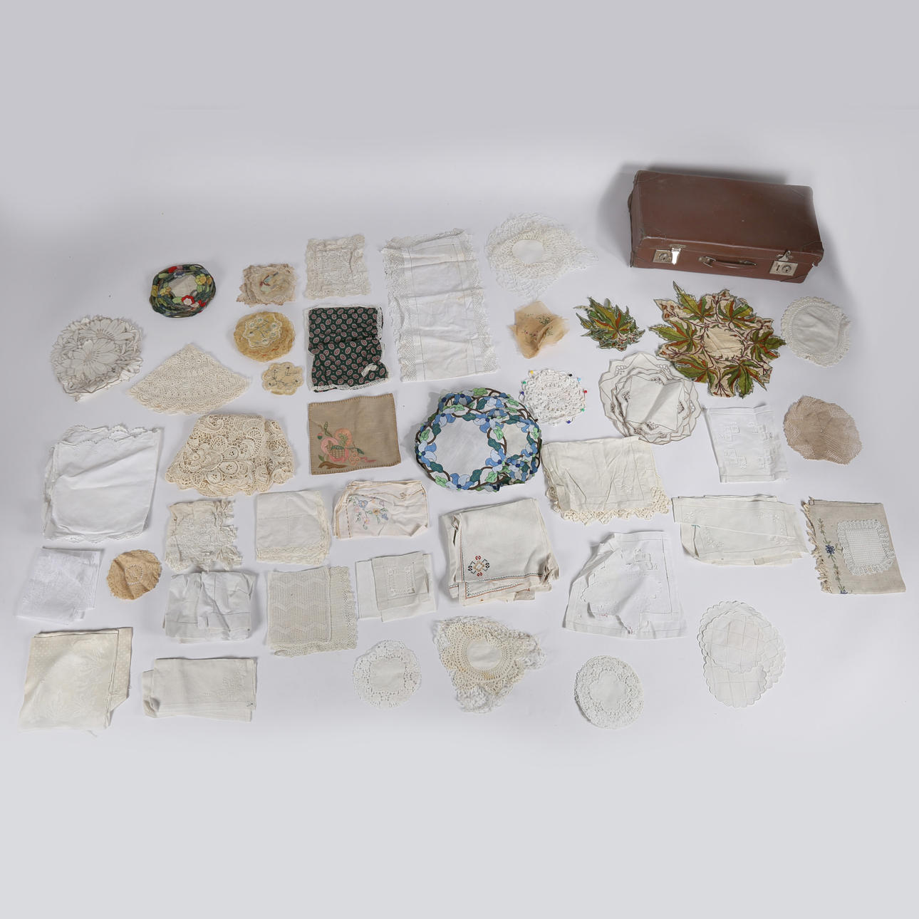 Lederkoffer mit einer Menge Spitze, mit Leinen bestickten Tischdecken, Deckchen und Untersetzern.