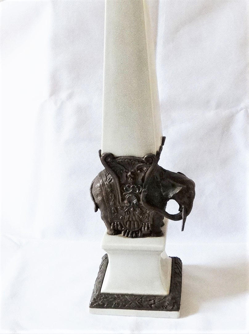 BRONZE ELEPHANT WITH CERAMIC OBELISK, AROUND 1900.
