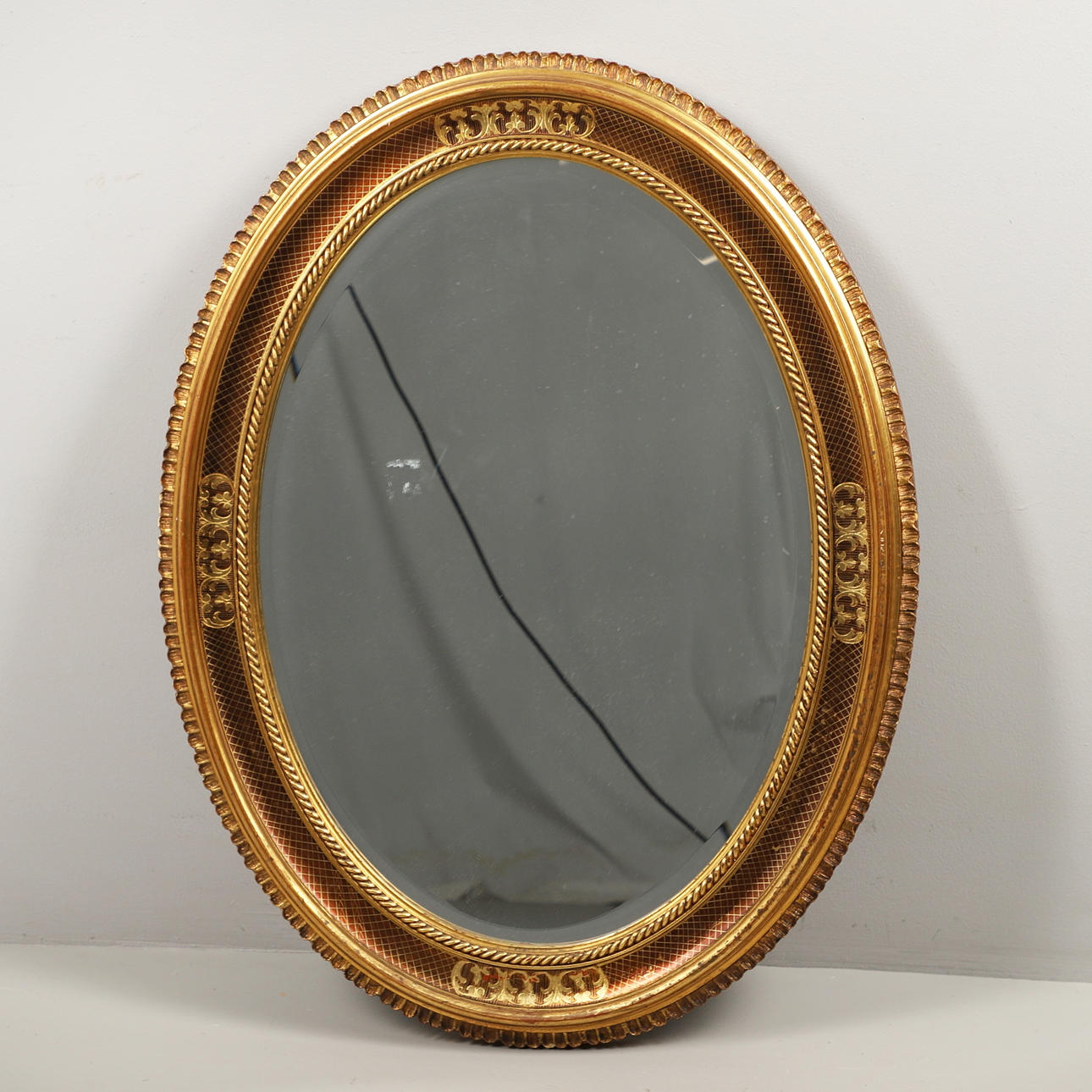 AN OVAL GILT FRAMED MIRROR.