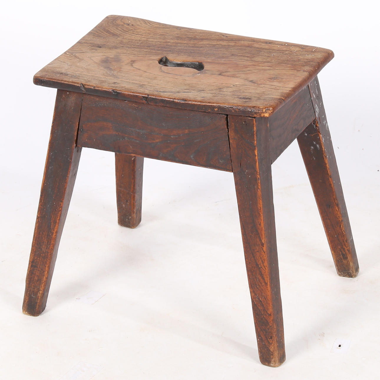 A VICTORIAN ELM FOUR LEGGED STOOL.