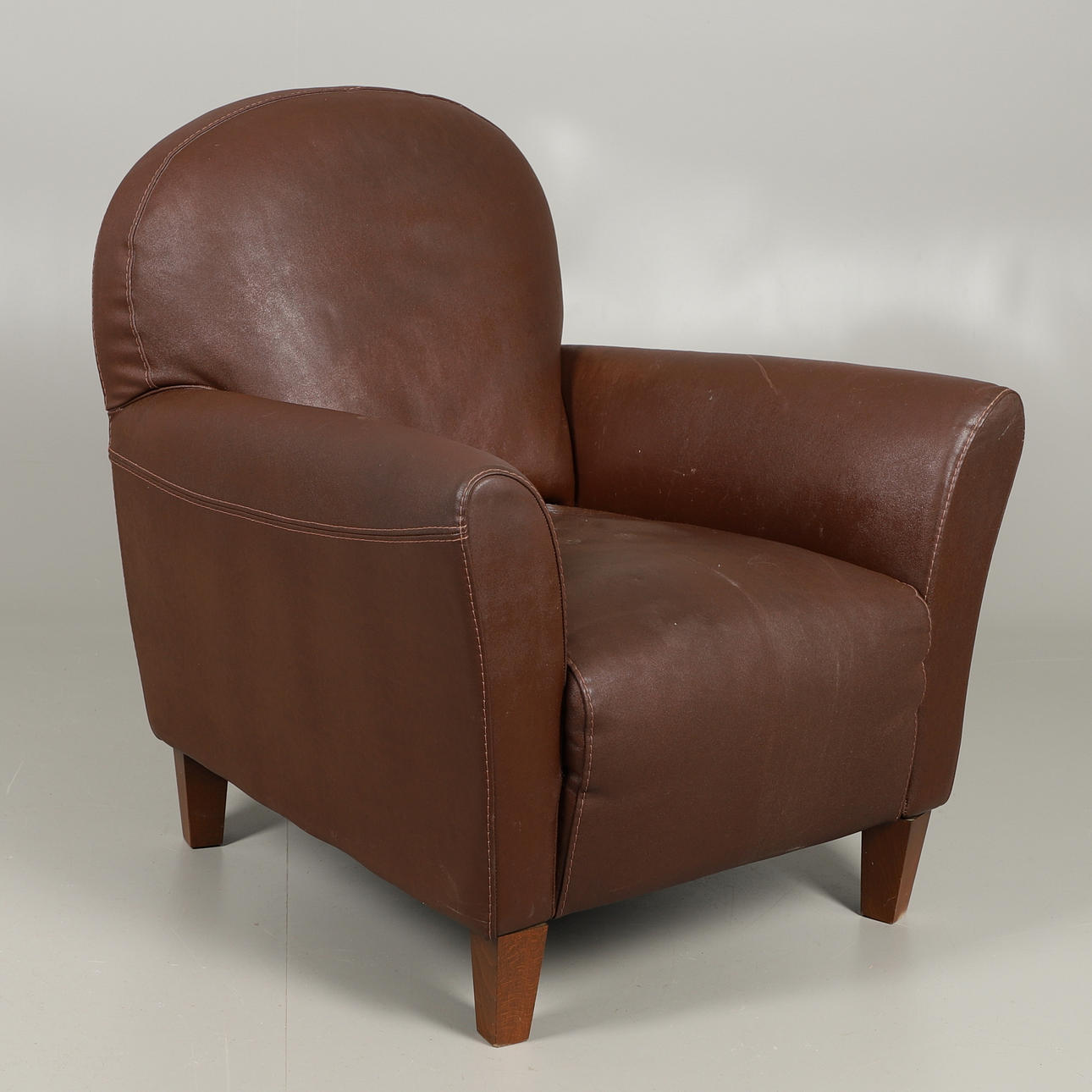 EN MODERN BRUN LÄDERFÅTÖLJ.