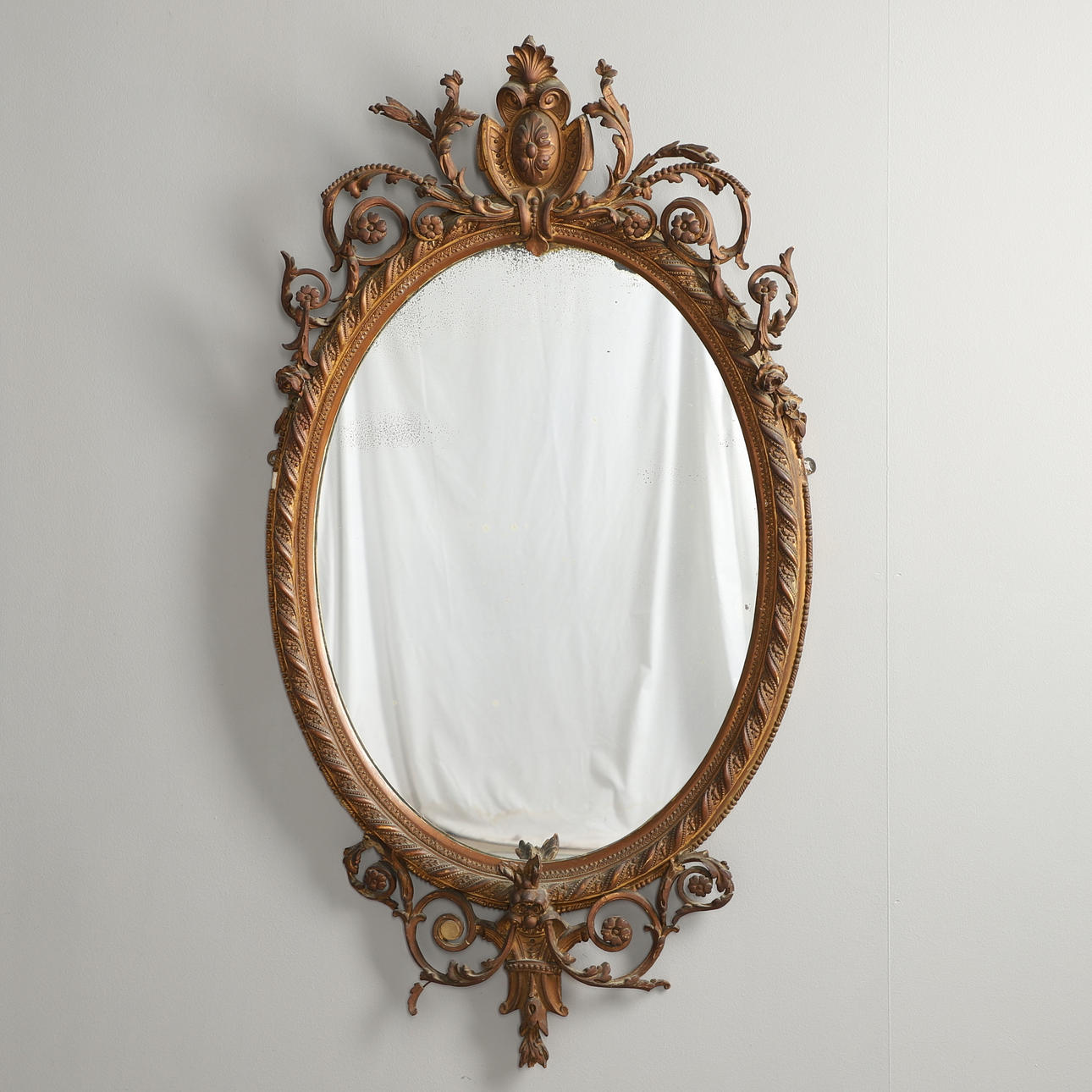 A 19TH CENTURY OVAL GILT GESSO WALL MIRROR.