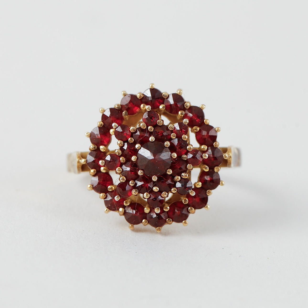 A RING, low content gold approx. 9 k and garnets.