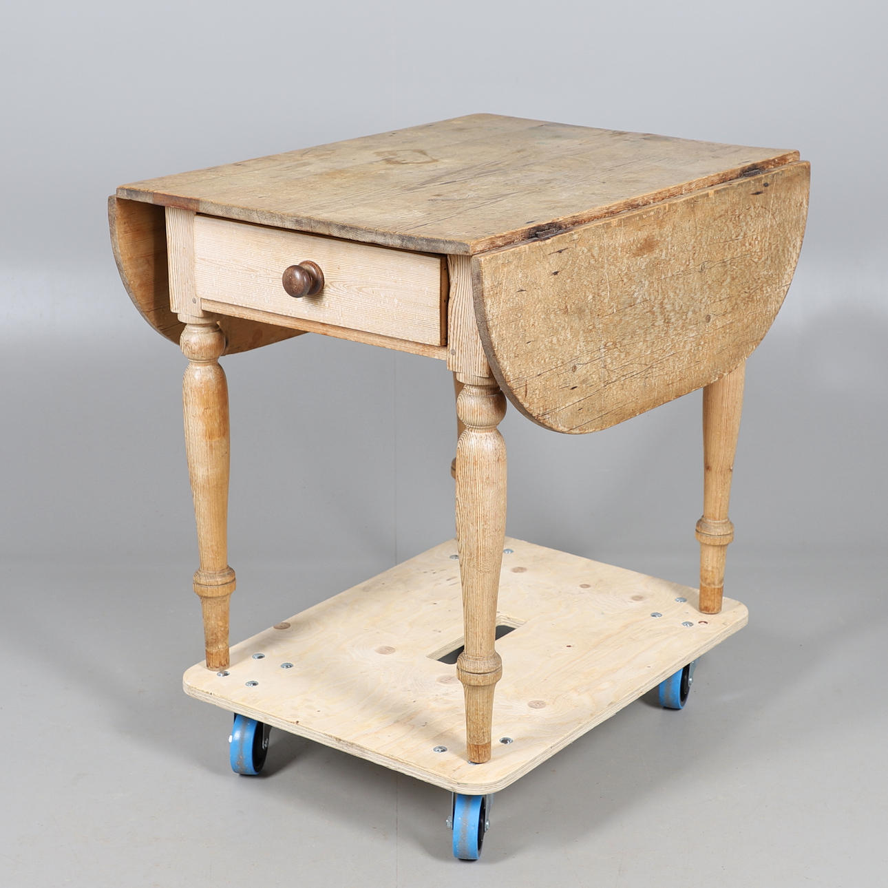 UNA MESA RÚSTICA DE PINO CON SOLAPA ABATIBLE.