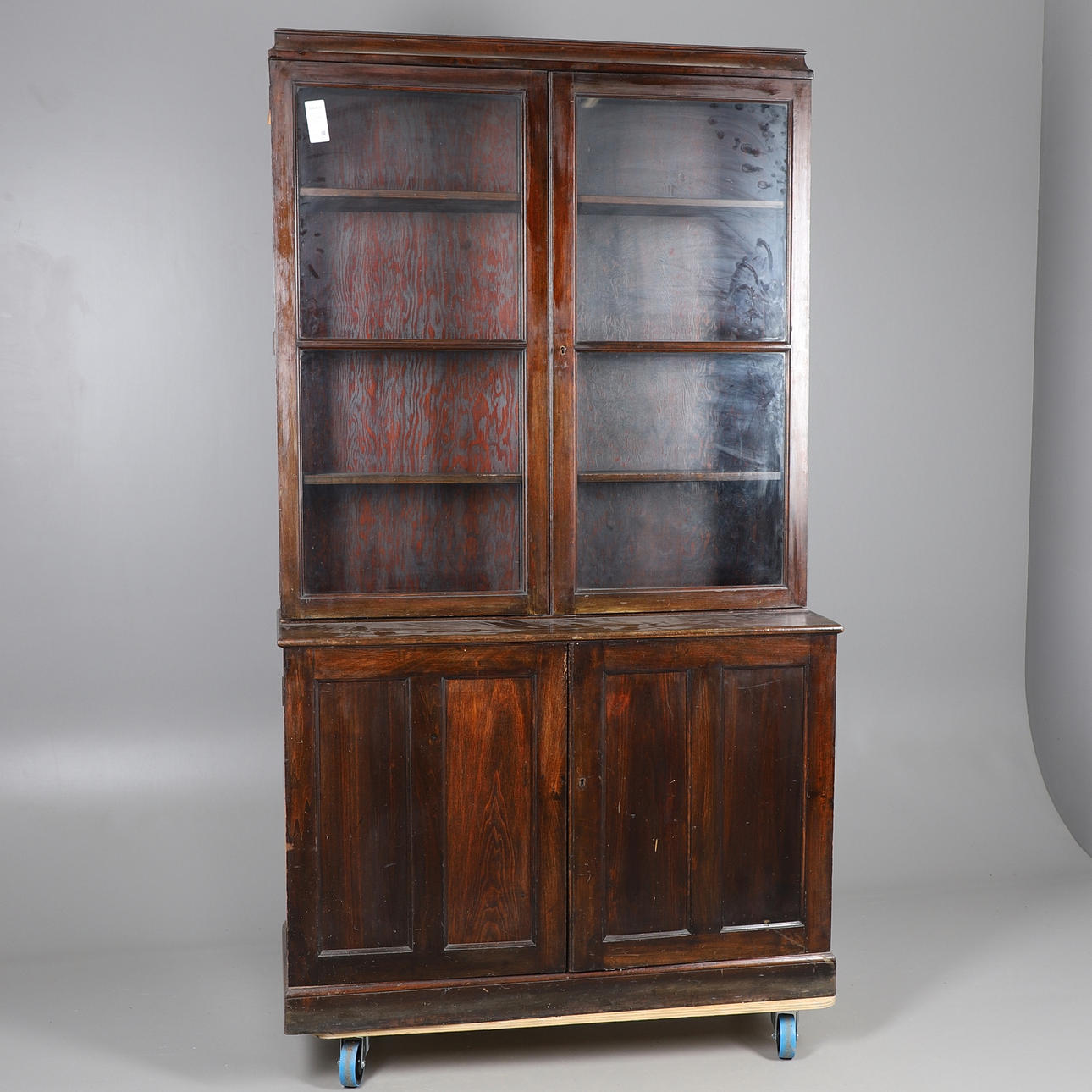 A STAINED PINE BOOKCASE WITH GLAZED UPPER SECTION.