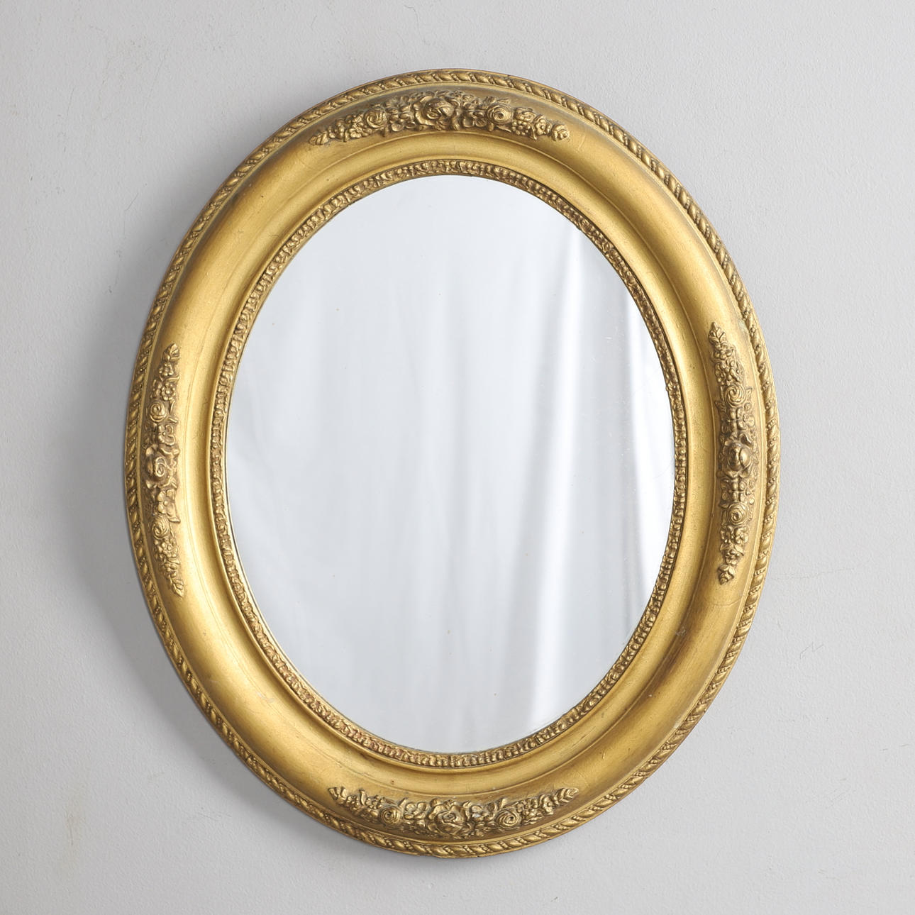 AN EDWARDIAN GILT FRAMED OVAL WALL MIRROR.