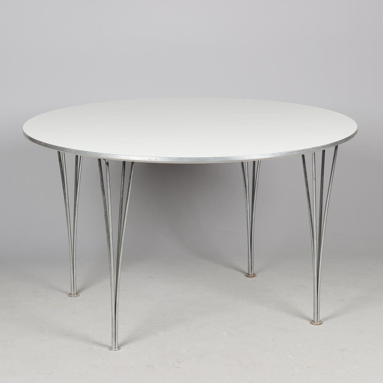 PIET HEIN, BRUNO MATHSSON. Circular/round table, white laminate, alloy edge, tension legs. Fritz Hansen, Denmark.