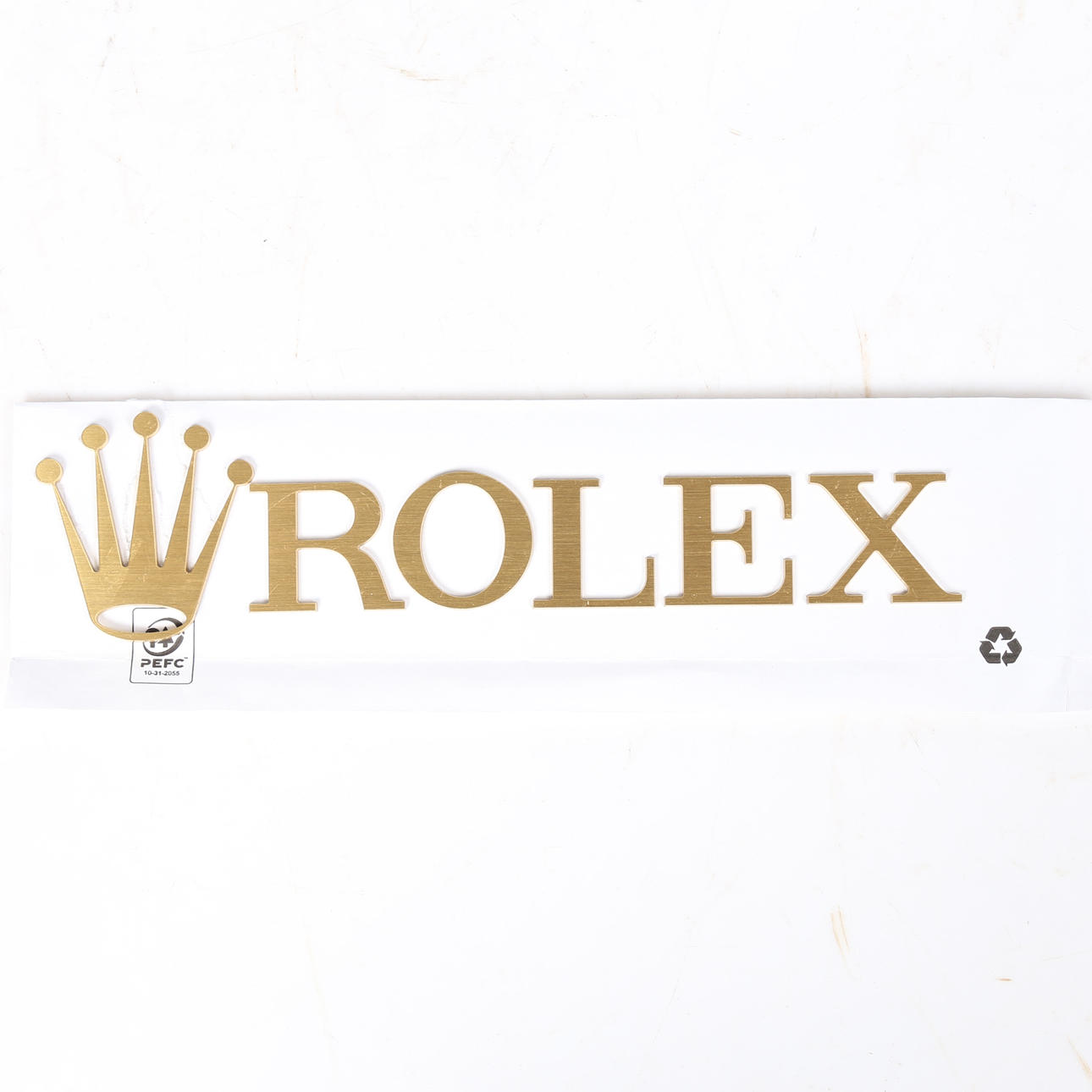 A BRASS ROLEX CROWN EMBLEM AND LETTERS.