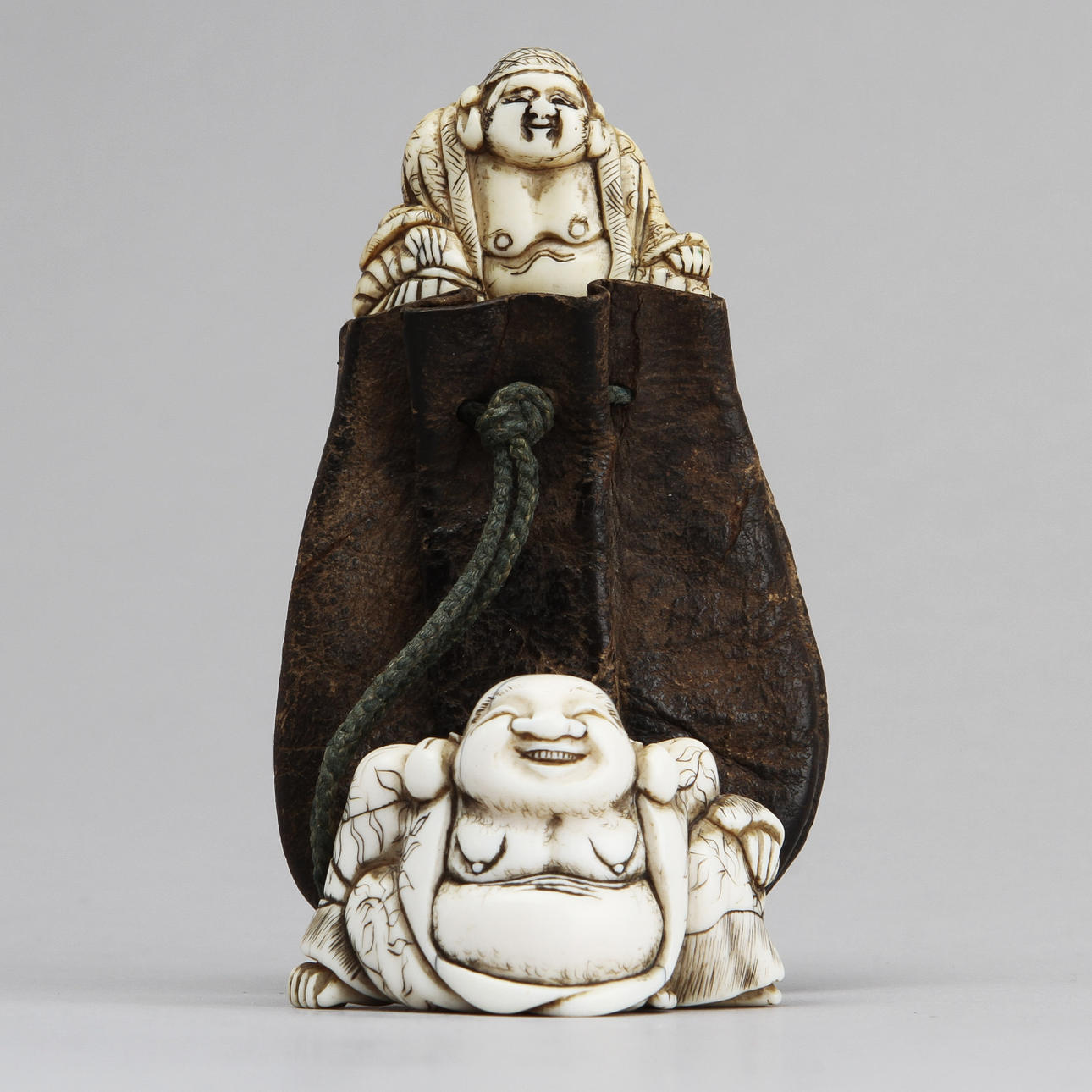 NETSUKE, 2 st, en med tobakspung. Omkring sekelskiftet 1800/1900-tal.