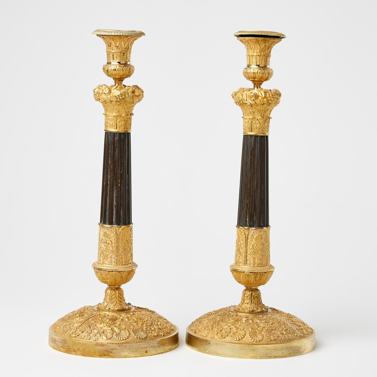 A pair of Restoration candlesticks, probably Parisian works of the first half of the 19th century, burnished gilt and dark patinated bronze.