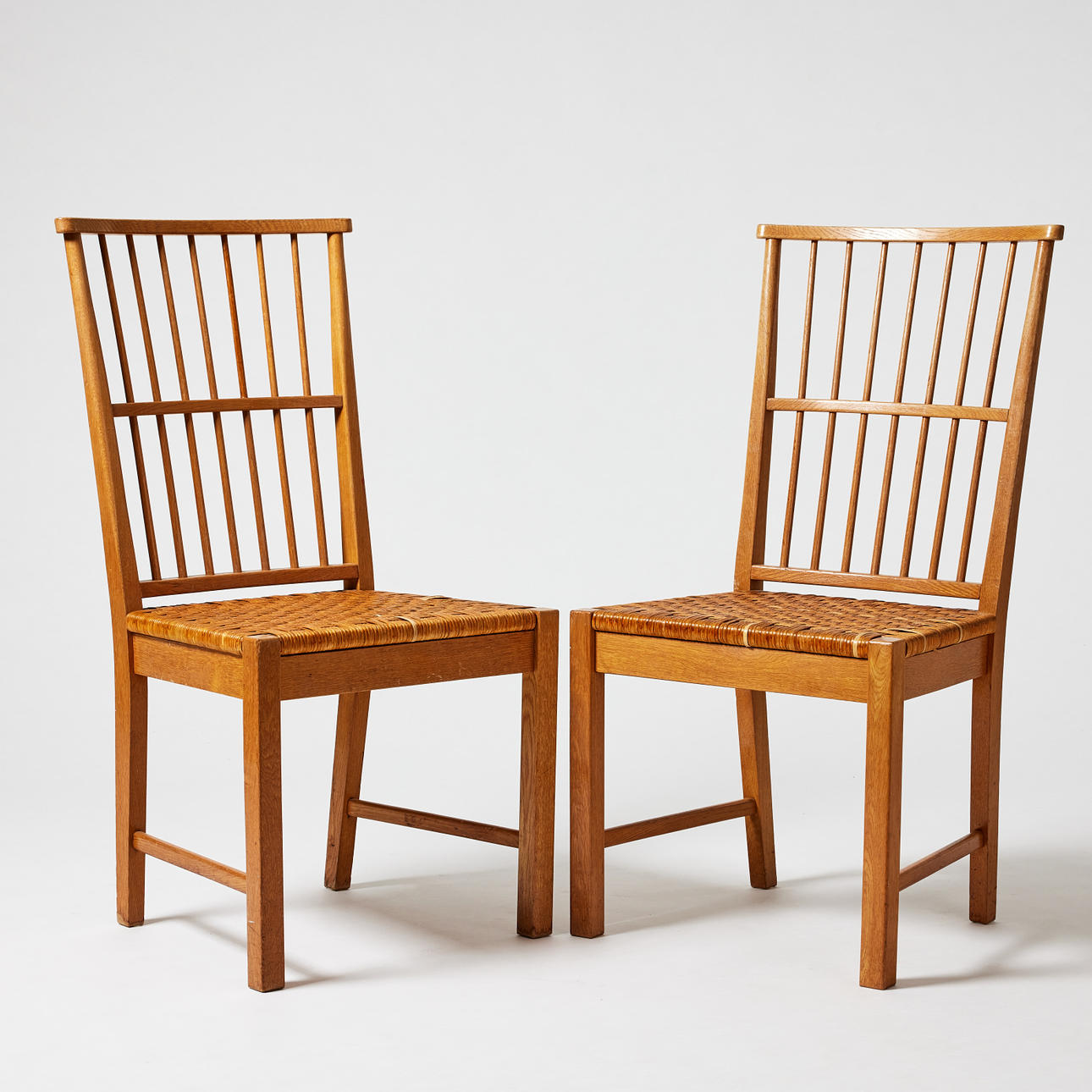 A pair of Fritz Hansen Danish oak chairs with wicker rattan seats.