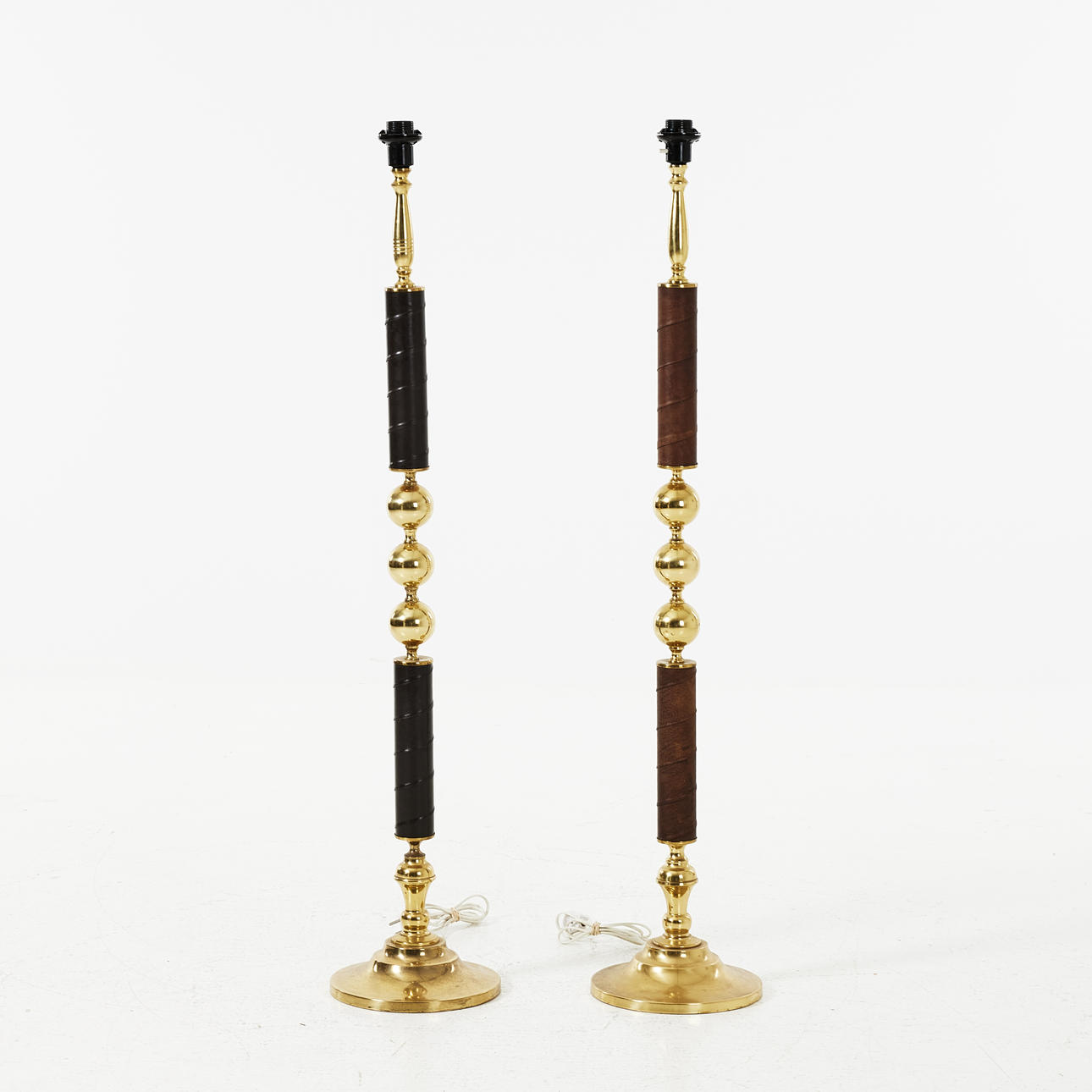 A pair of brass floor lamps, partly clad in leather, second half of the ...