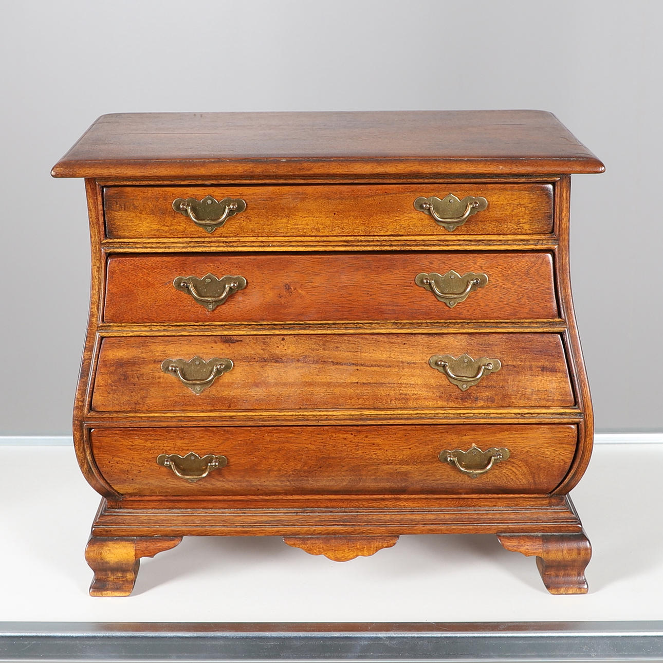 EINE BOMBENFÖRMIGE KOMMODE MIT MINIATUR-TISCHPLATTE.