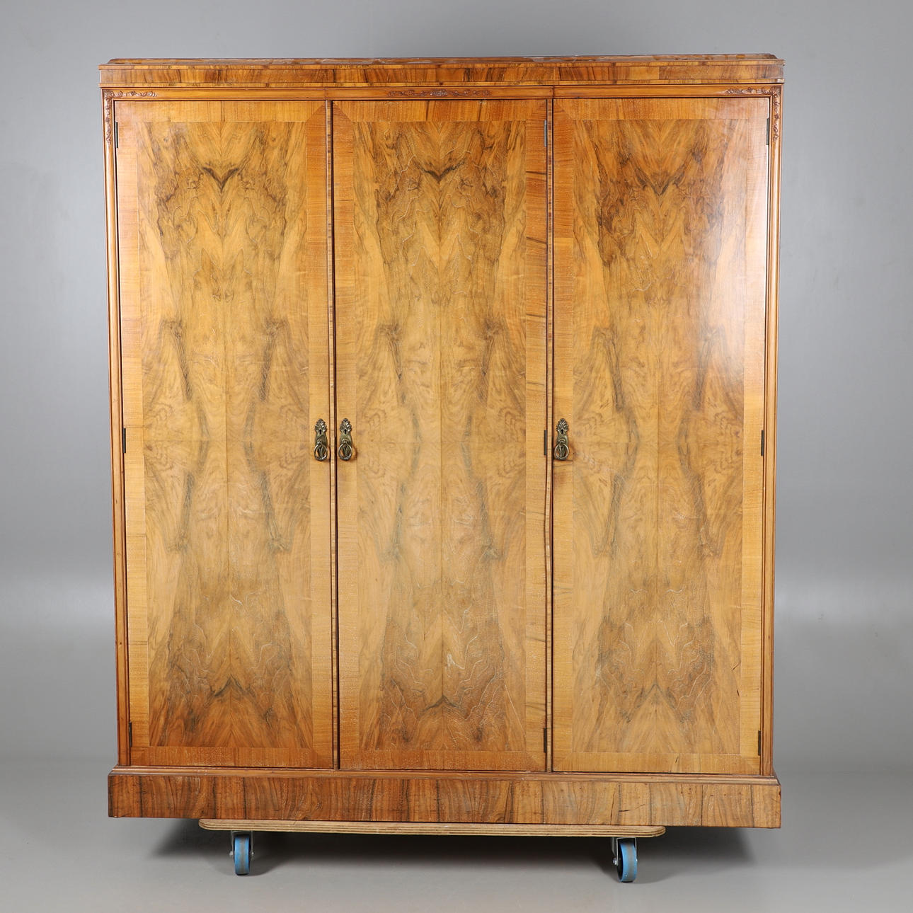 EIN DREITÜRIGER KOMPAKTER KLEIDERSCHRANK AUS GESCHNITZTEM NUSSBAUM.