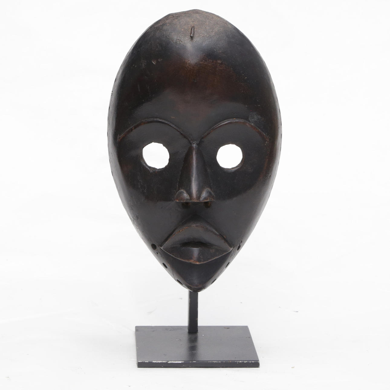 Eine hölzerne Tanzmaske, Afrika, auf einem Ständer.