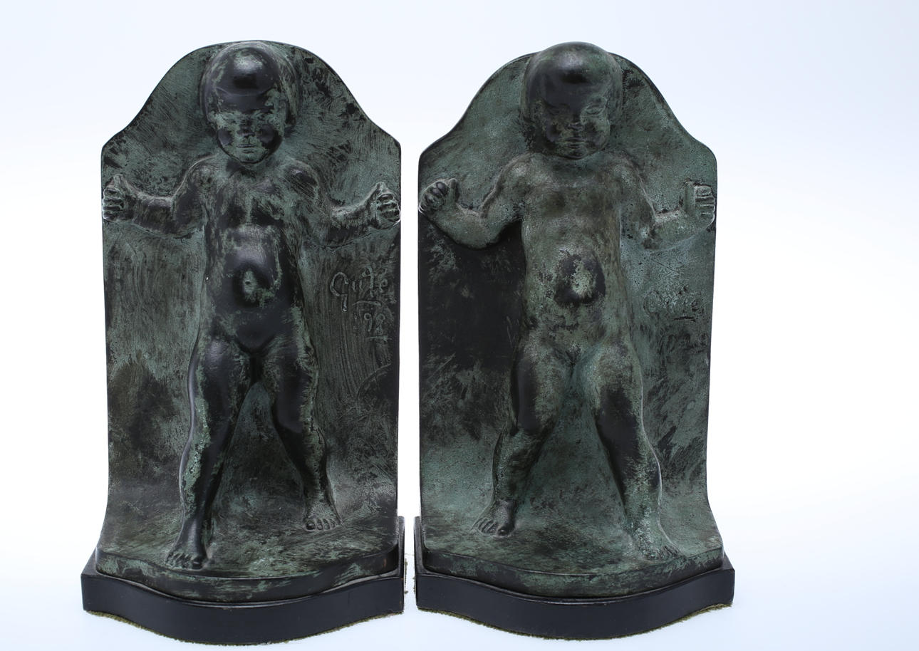 AXEL GUTE. Bokstöd, ett par patinerad brons av stående naken gosse på träsockel, signerad Gute 1929.