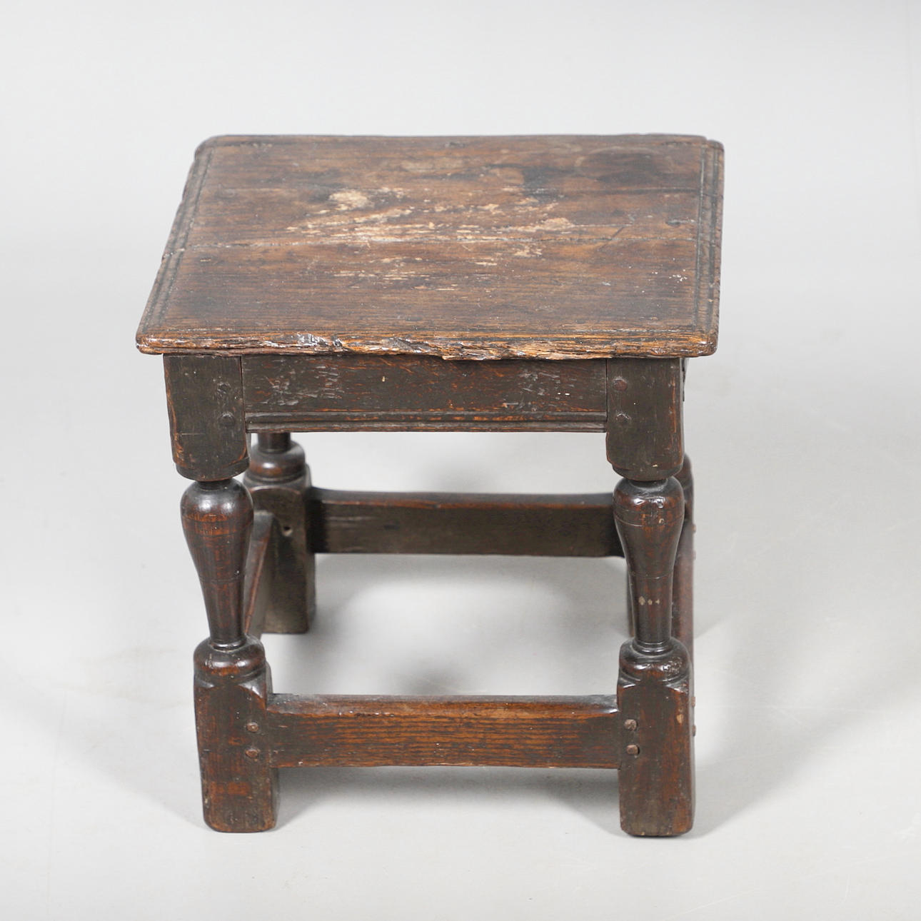 A SEVENTEENTH CENTURY OAK LOW STOOL.