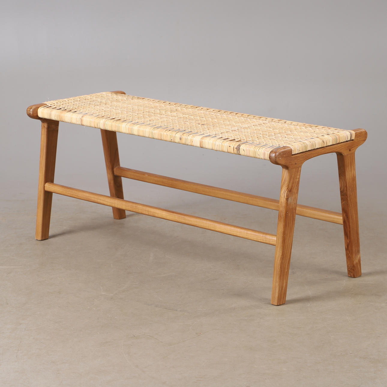 A contemporary teak and rattan bench.