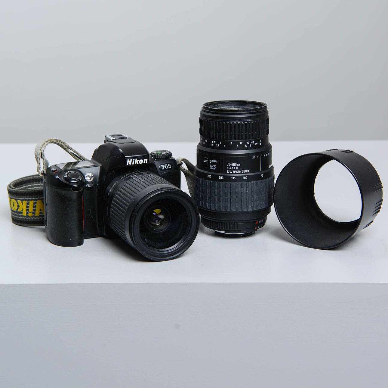 Kamera Nikon F-65, jossa 2 objektiivia.