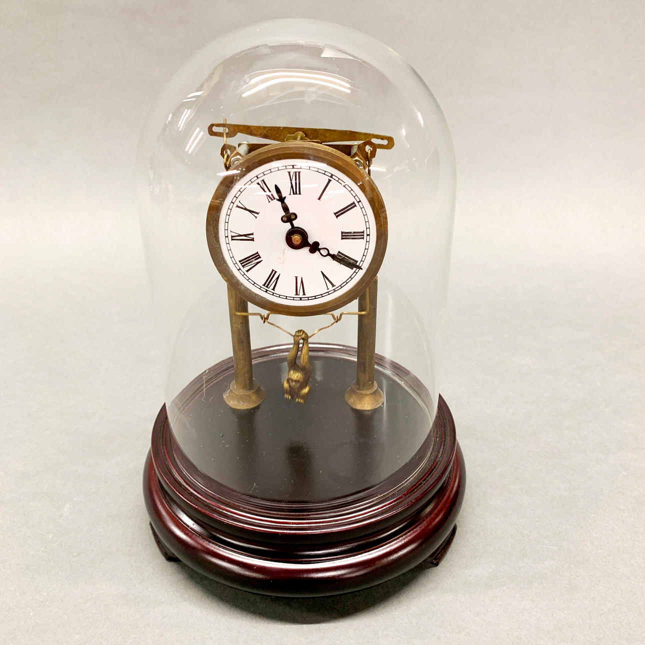 CLOCK UNDER DOME WITH SWINGING MONKEY PENDULUM.