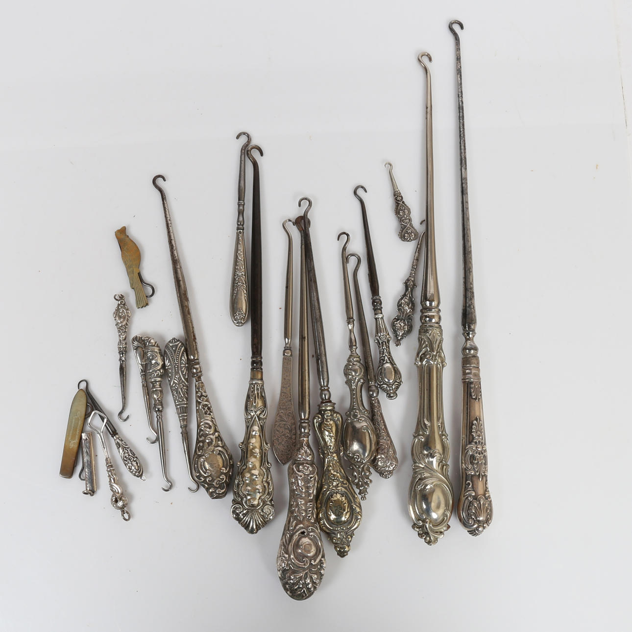 A COLLECTION OF WHITE METAL HANDLED BUTTON HOOKS (QTY).
