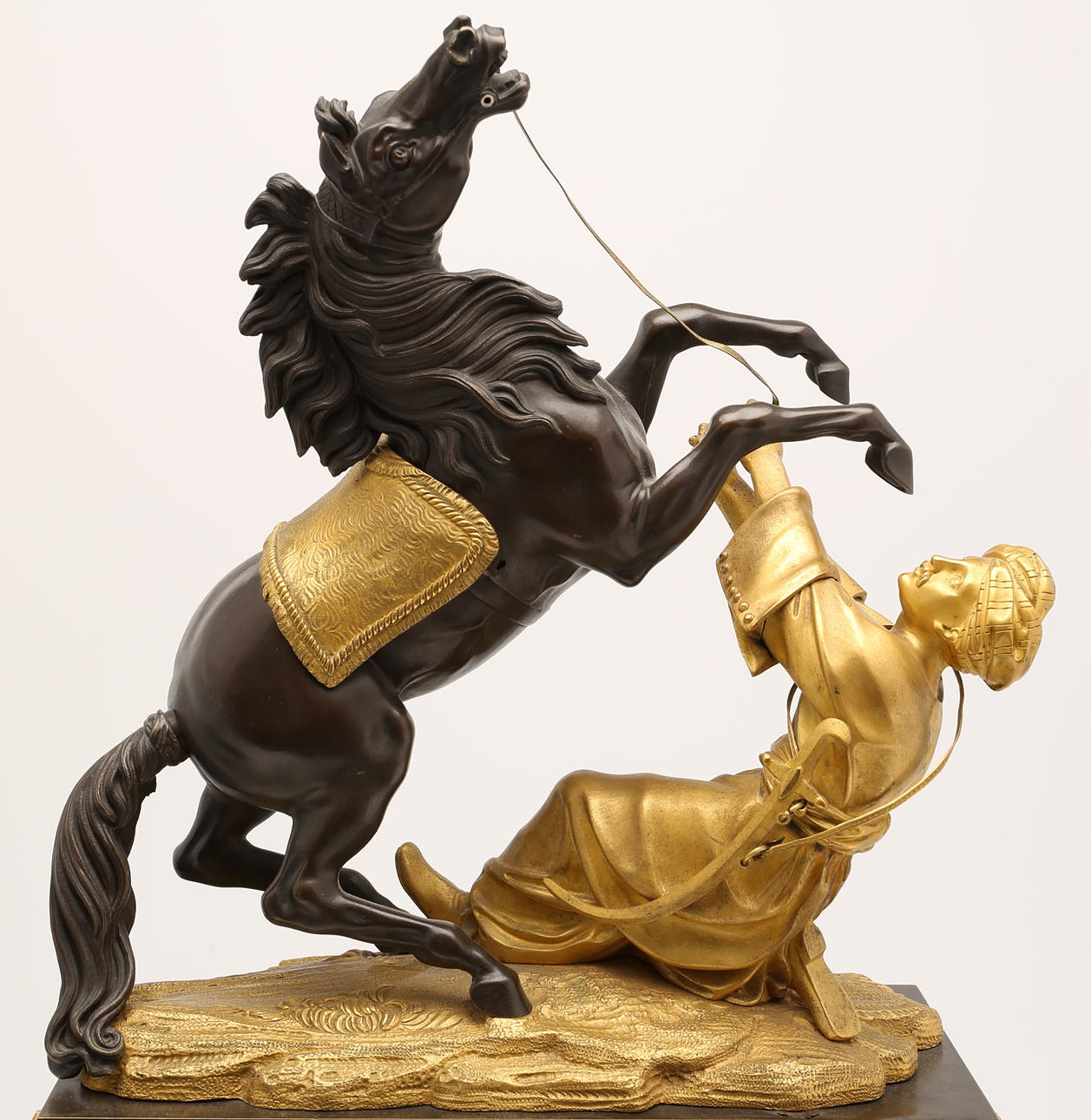 BORDSPENDYL, förgylld och patinerad brons. Krönt av ottomansk mansfigur i turban med stegrande häst. Empire.