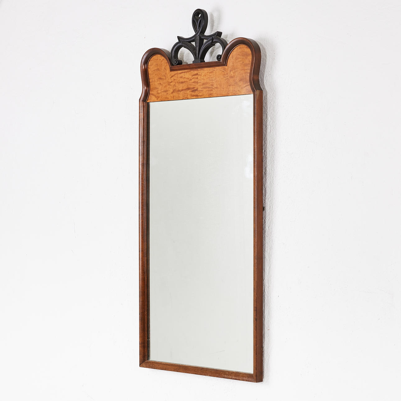 A mirror, first half of the 20th century, Swedish Grace, stained beech frame, veneered in birch, stylized blackened crown.