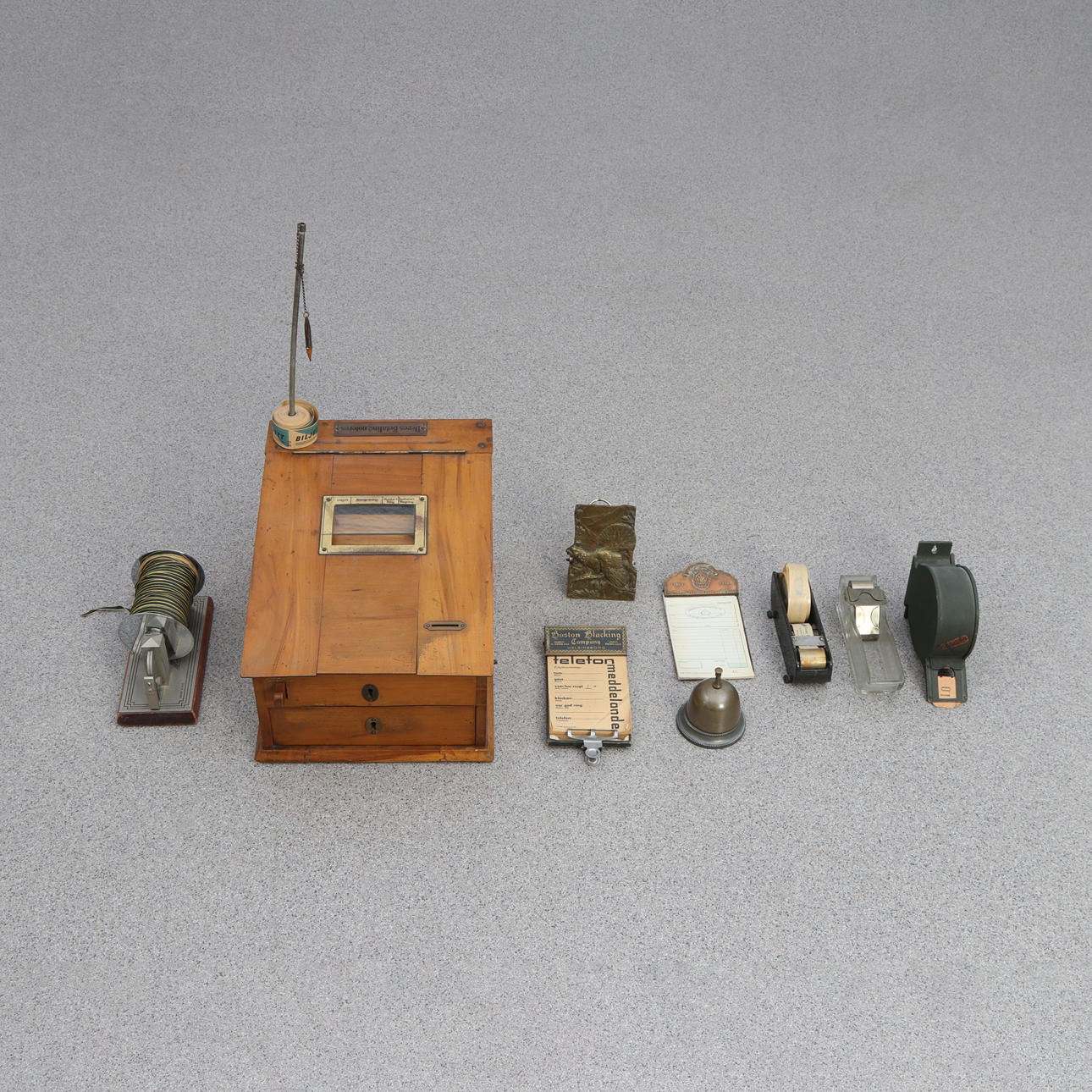BUTIK TILBEHØR, NI STYKKER. Kasseboks, kvitteringsholder, nummerplader m.m. 20. århundrede.
