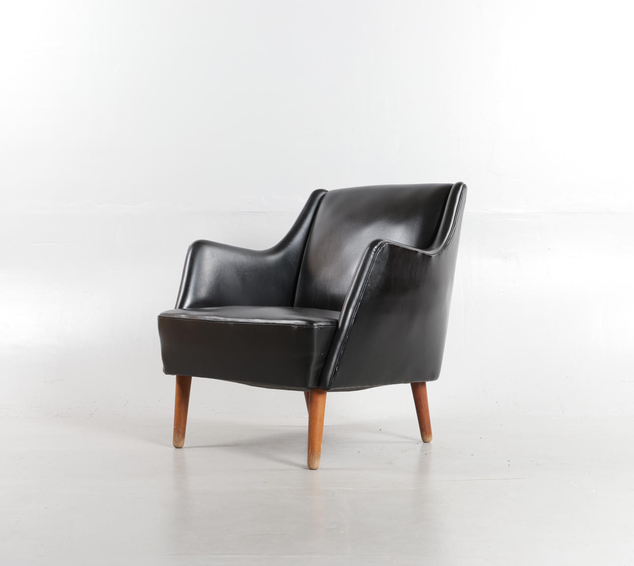 DANSK MØBELDESIGN. Armchair upholstered with black skai, round legs of teak, 1950-60s. Furniture - Armchairs & Chairs
