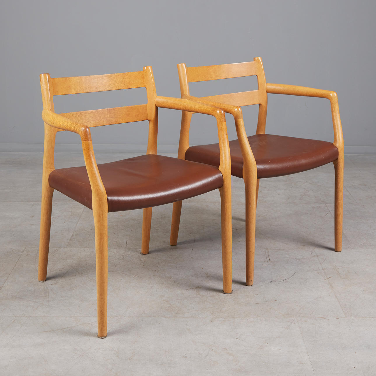 NIELS O. MØLLER. för J.L. MØLLER, två stolar/armstöd, modell '67' ek, läder, 1960-tal, Danmark (2).