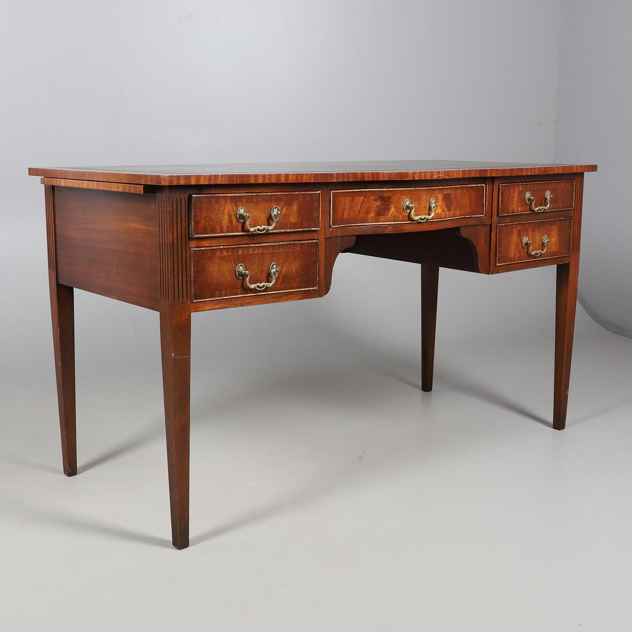 A REPRODUCTION LEATHER TOPPED WRITING DESK.