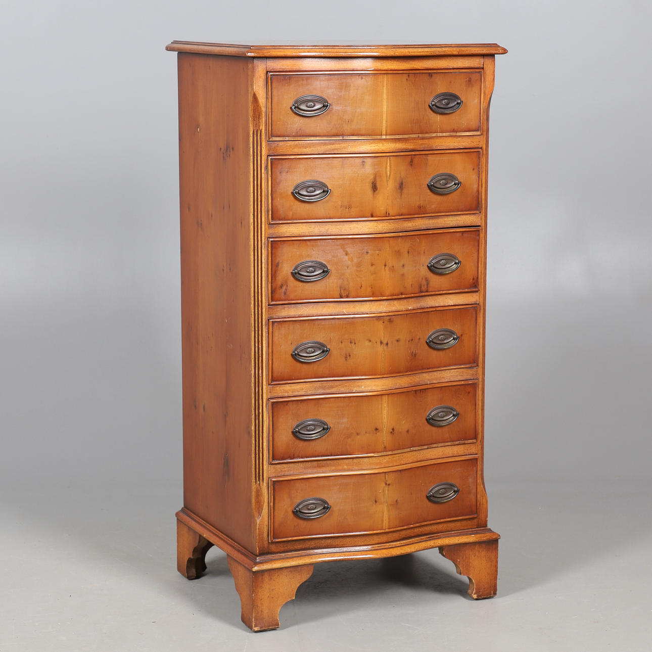 EINE KOMMODE MIT SERPENTINENFRONT UND SECHS SCHUBLADEN IN EIBENOPTIK.
