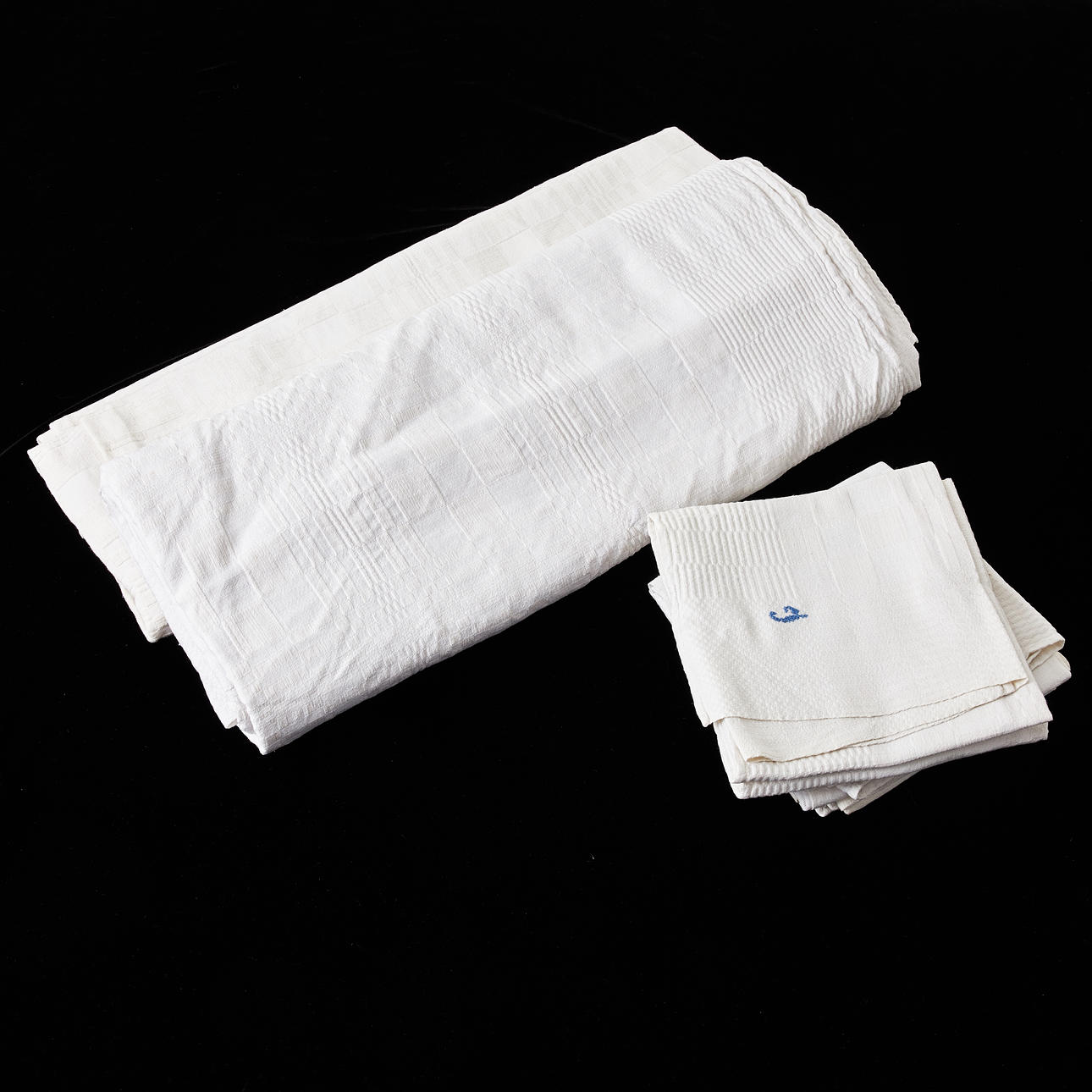 TABLECLOTHS 2 pcs. with NAPKINS, 8 pcs., half-linen, drail, around the turn of the century 1900, embroidered monogram (J) in white and blue respectively.