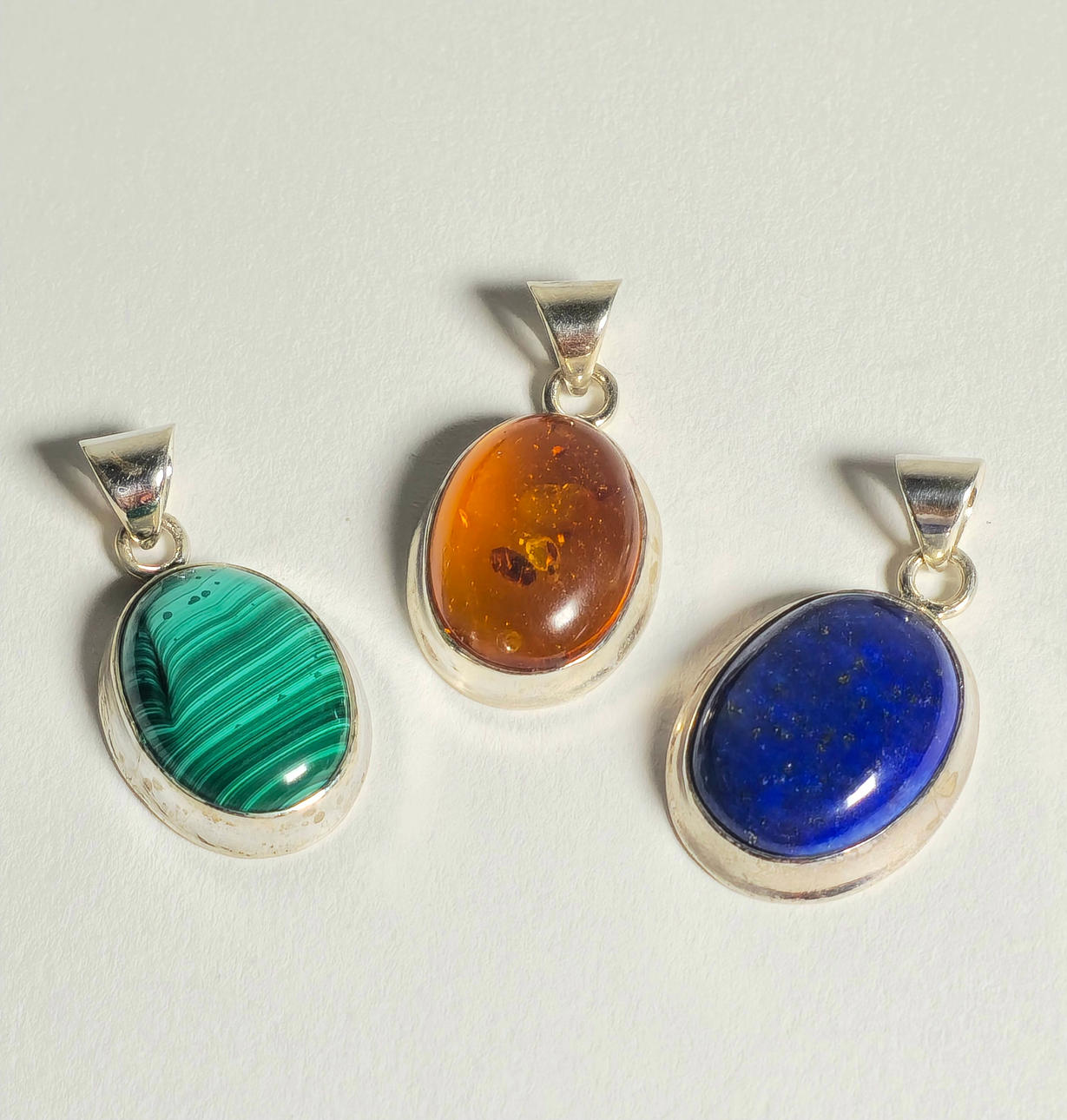 DREI SILBERNE ANHÄNGER MIT MALACHIT, LAPISLAZULI UND BERNSTEIN.