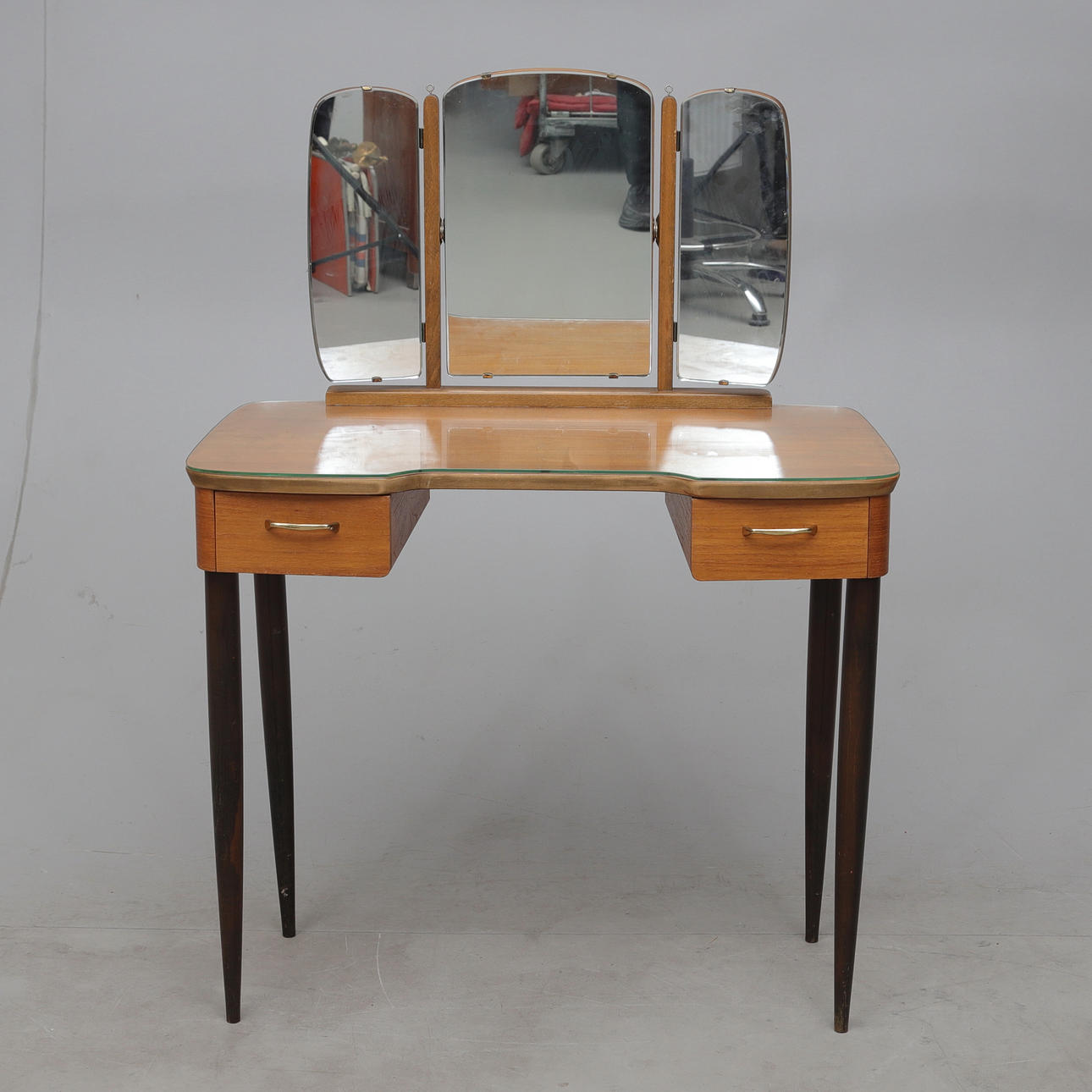 A 20th century teak veneer dressing table with glass top.