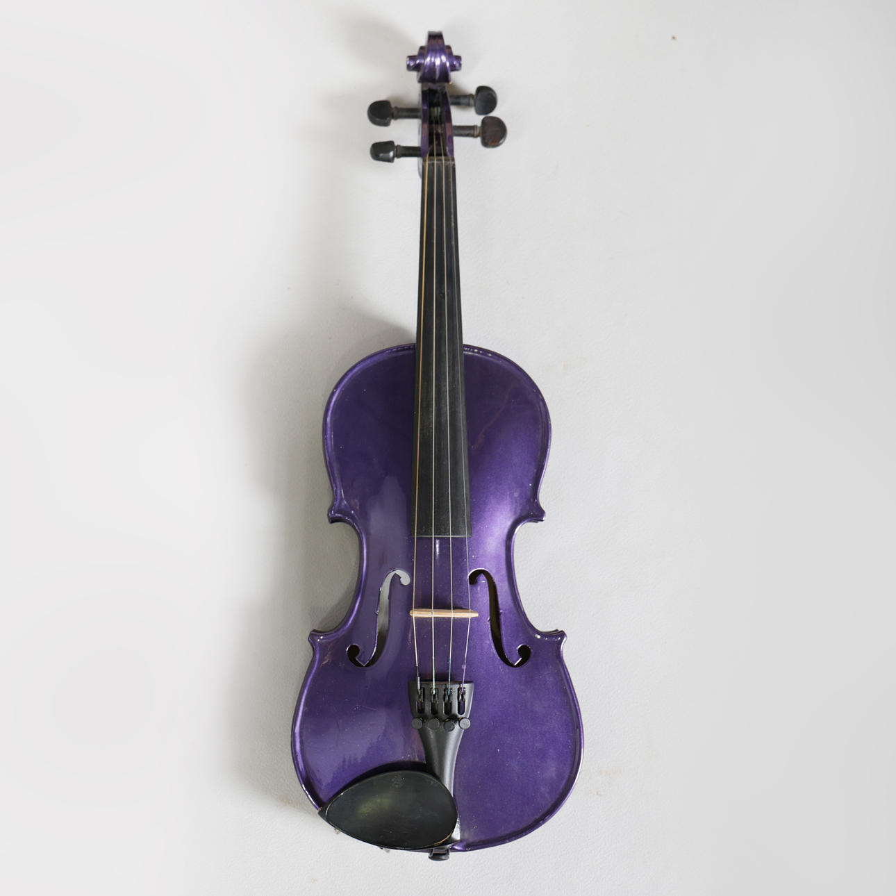 A CASED 1/2 PURPLE VIOLIN WITH TWO BOWS.